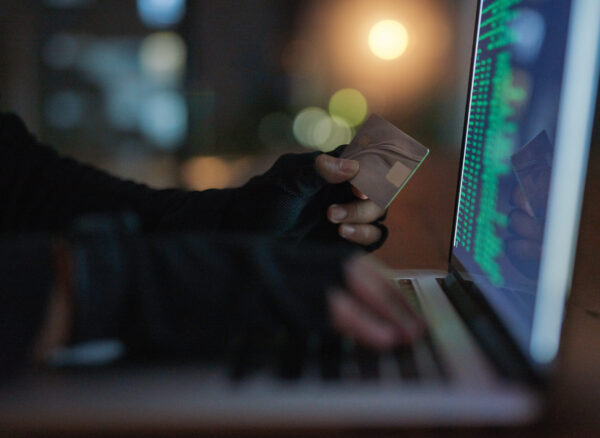 Shot of an unrecognisable hacker using a laptop to hack into a credit account.
