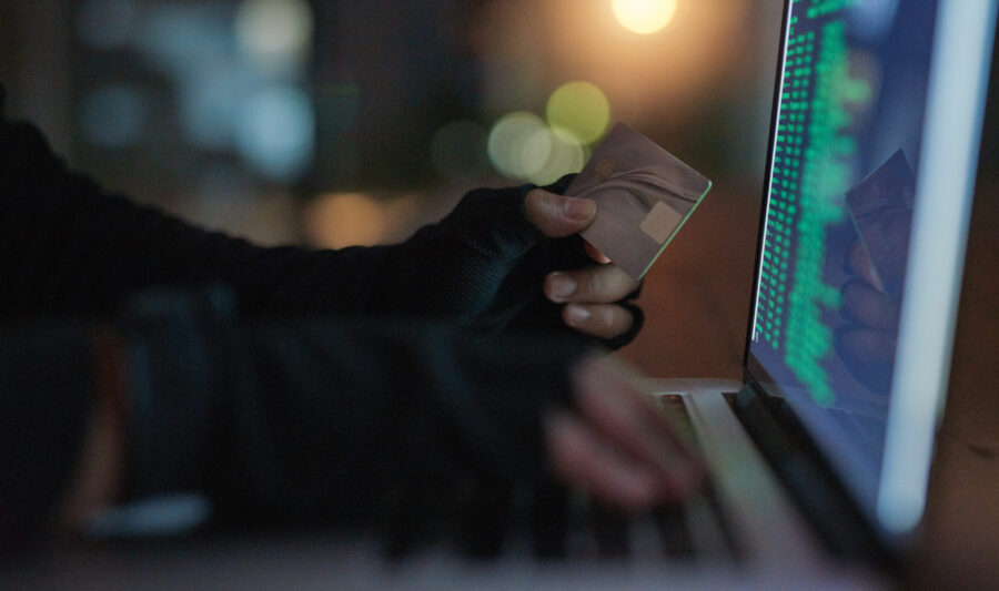 Shot of an unrecognisable hacker using a laptop to hack into a credit account. Shot of an unrecognisable hacker using a laptop to hack into a credit account.
