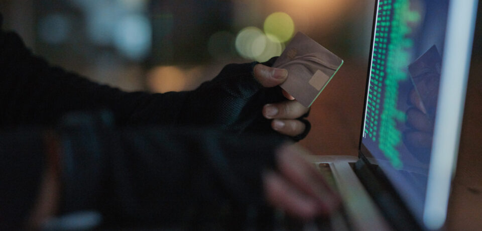 Shot of an unrecognisable hacker using a laptop to hack into a credit account.