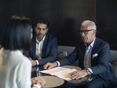 Two businessmen sitting in hotel table meeting with businesswoman Business professionals engaged in a serious discussion.