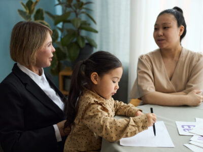 Educating Young Child with Teacher and Parent Observing Child engaging in learning activities at table with teacher and parent observing attentively