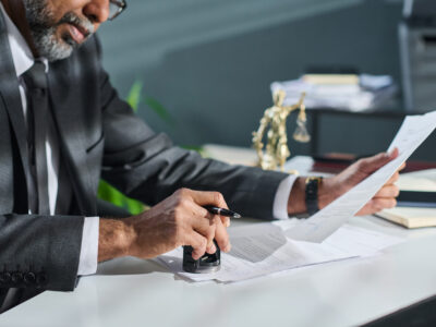 Lawyer putting stamp on documents Cropped shot of mature male adviser or director of company putting stamp on documents while sitting by workplace in office