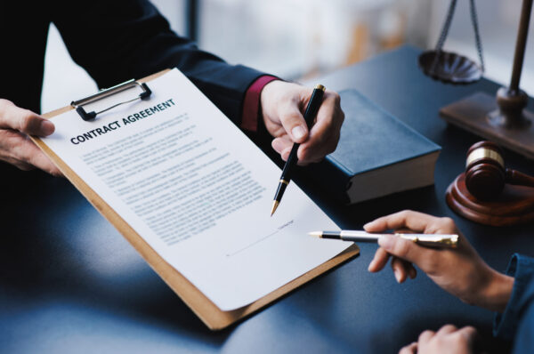 Lawyer working with client discussing contract papers with brass scale about legal legislation.