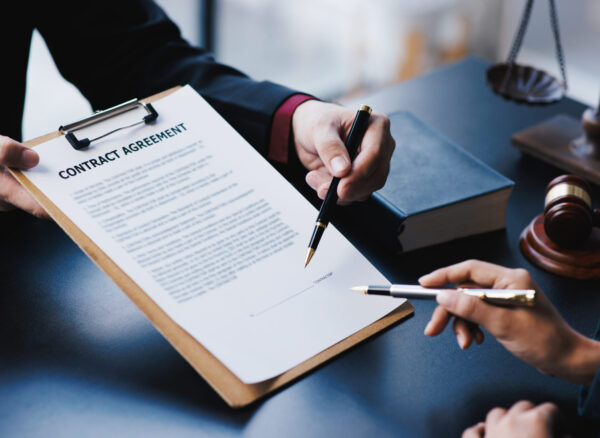 Lawyer working with client discussing contract papers with brass scale about legal legislation.