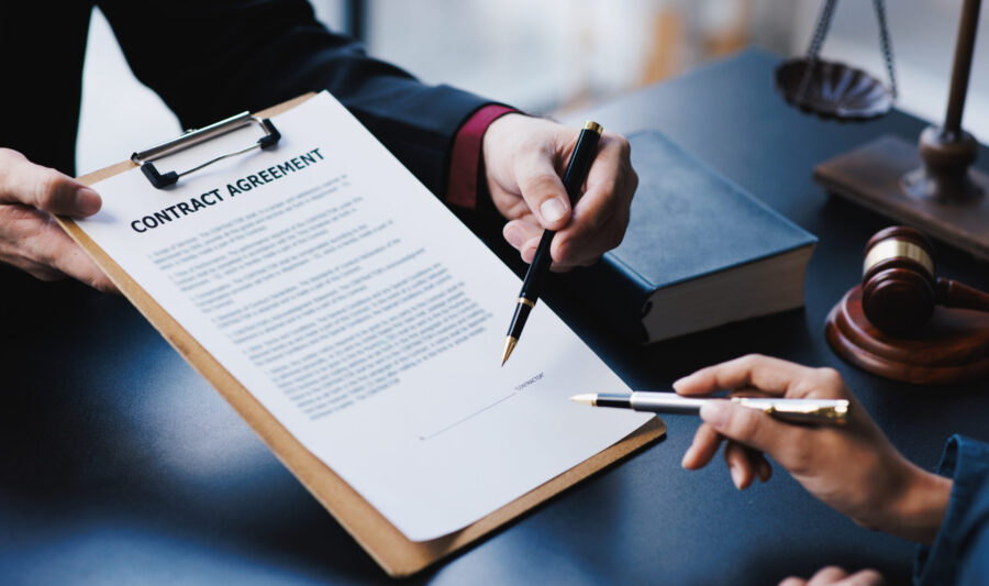 Lawyer working with client discussing contract papers with brass scale about legal legislation.
